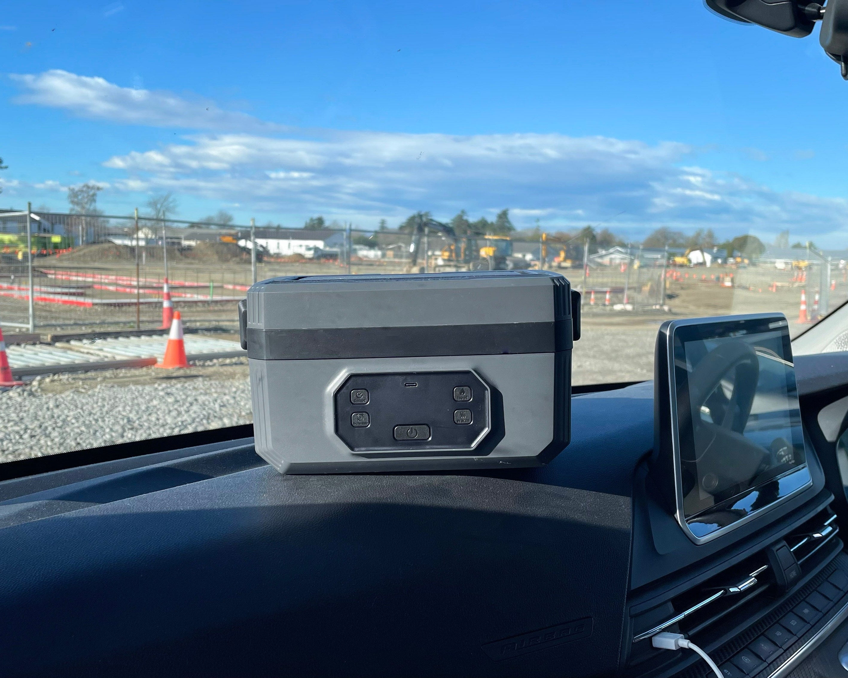 Norva Wireless Heated Lunchbox sitting on dashboard of van in construction site. 