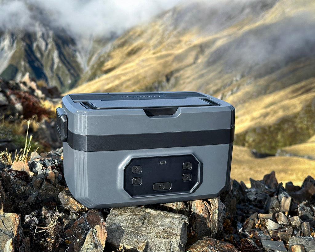 Norva Wireless Heated Lunchbox sitting on some rocks, with a mountain in the background. 